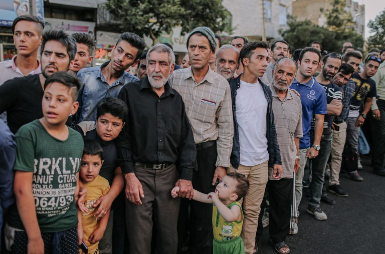 A group of people have gathered in the street to watch the show and humiliate the thugs by the police force